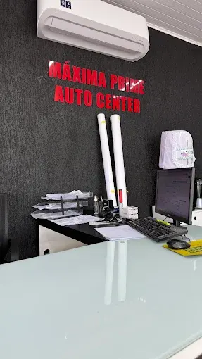 Balcão da recepção com a logomarca Máxima Prime Auto Center na parede escura