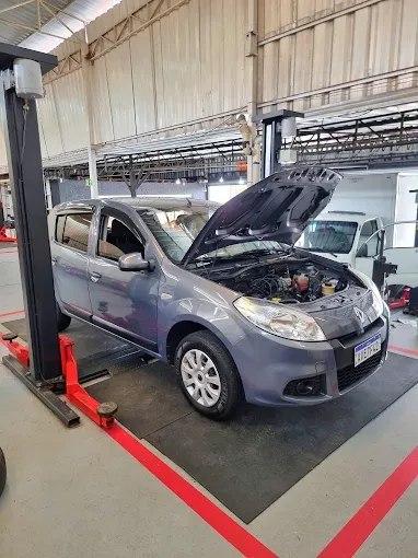 Carro cinza com o capô aberto sobre o elevador da oficina Máxima Prime Auto Center