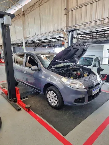 Carro com o capô aberto sobre o elevador da oficina
