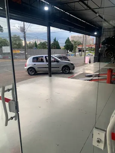 Entrada do galpão da oficina vista de dentro, com piso claro e vista para a rua