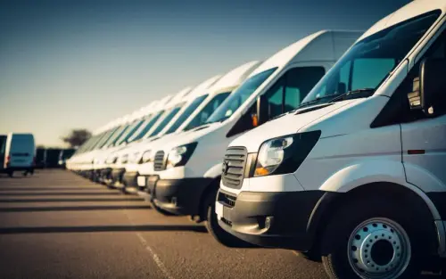 Fileira de vans brancas de frota empresarial estacionadas lado a lado em um pátio