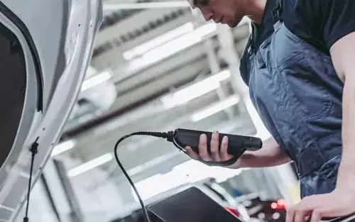 Mecânico conectando um scanner e um notebook ao carro para o diagnóstico da injeção eletrônica