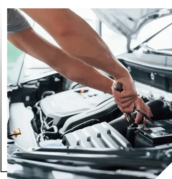 Mecânico segurando uma chave de catraca sobre o motor de um carro com o capô aberto durante manutenção