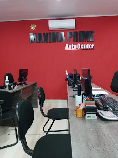 Recepção com parede vermelha, a logomarca Máxima Prime Auto Center, mesas e cadeiras