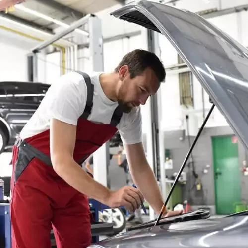 Mecânico inspecionando o motor de um carro com o capô aberto durante a revisão